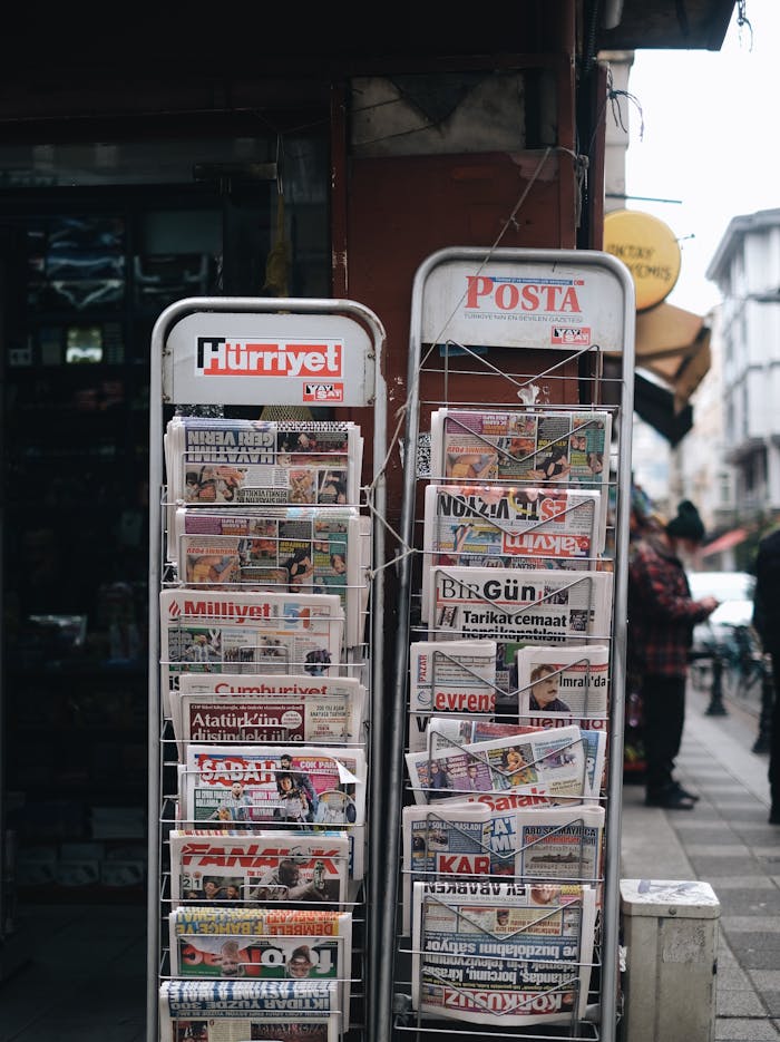 Outdoor newspaper stand displaying various Turkish publications on a street.